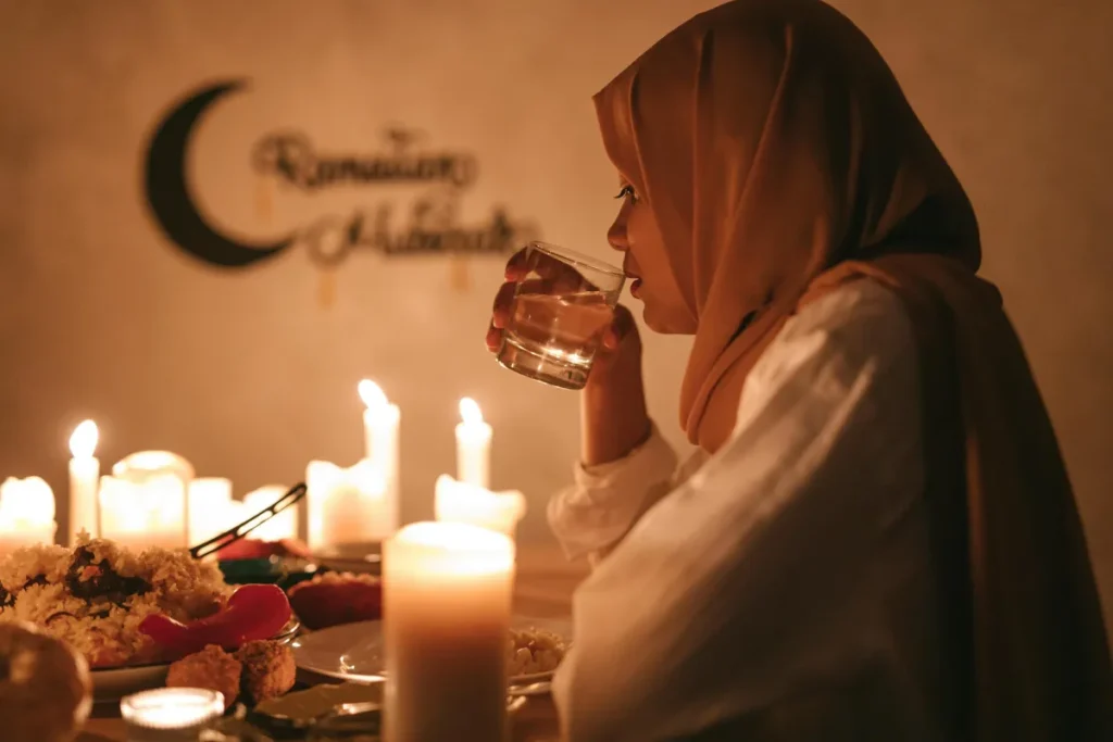 Wanita berhijab berbuka puasa di meja makan dengan lilin pada suasana Ramadan