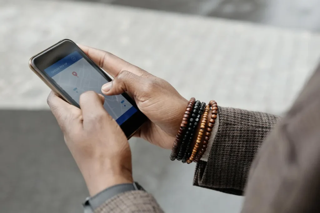 Tangan memegang smartphone dengan aplikasi GPS aktif untuk melacak lokasi perangkat